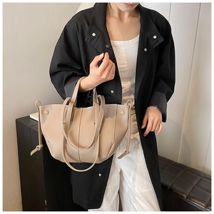 Detailed view of the lychee grain leather texture and wing-shaped folds on the beige tote bag
