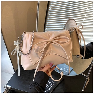 Detail of cream PU ballet-style bag with oversized bow and elegant silver chain strap