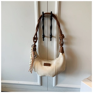 Detail of cream leather hobo bag with brown braided strap and striped tassel ornament