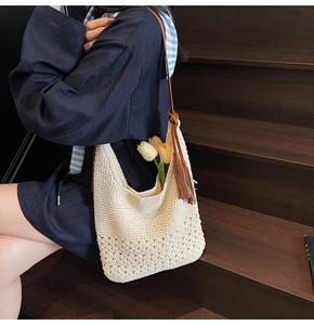 Detail of hand-woven cream tote bag with floral patterns and leather tassels