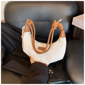 Detail of white dumpling bag showing brown knotted leather handle and metal accents