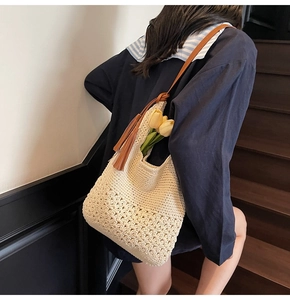 Detail of cream crochet tote bag with intricate petal weave and brown tassel accent