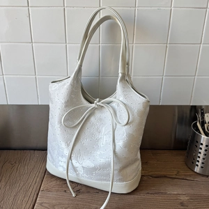 Close-up of white tote bag featuring intricate butterfly embroidery and a large ribbon bow