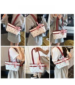 Dettaglio di una borsa a cuscino bianca con stampa a fiocchi rossi e ciondolo a cuore