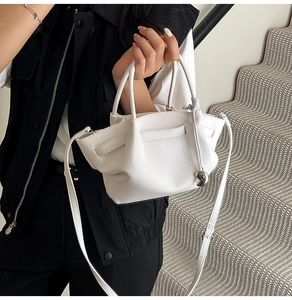 Detail of white lychee leather bucket bag with pleated design and silver heart charm
