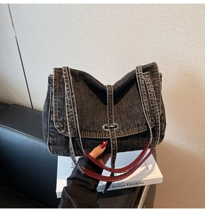 Détail d'un sac cabas vintage en jean noir avec boucle métallique et garniture rouge