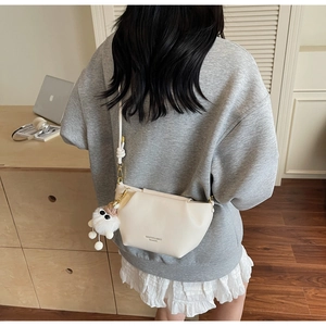 Détail du sac bandoulière blanc cassé avec un joli porte-clés en peluche