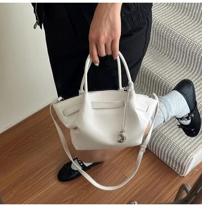 Close-up of white lychee leather bucket bag featuring soft pleats and silver heart charm
