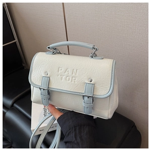 Detail der cremeweißen PU-Ledertasche mit geprägtem PAN 'TOR-Logo und Klappverschluss