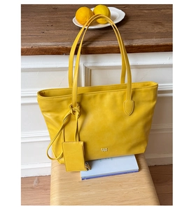 Detail of yellow lychee-grain tote bag with knotted handles and a mini charm pouch
