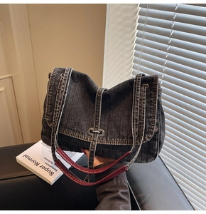 Détail du sac cabas en jean foncé avec poignées en cuir rouge et boucle en métal