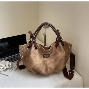 Dettaglio di una grande borsa marrone testurizzata con etichetta su tavolo bianco