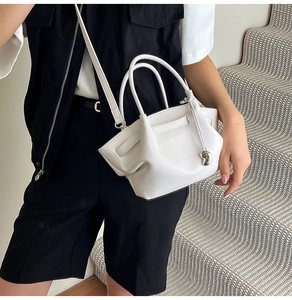 Detail of white lychee grain bucket bag with silver heart charm and pleated texture