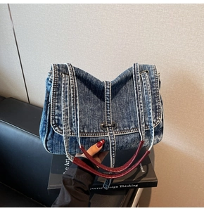 Détail du sac cabas vintage en denim avec poignée en cuir rouge et boucle en métal