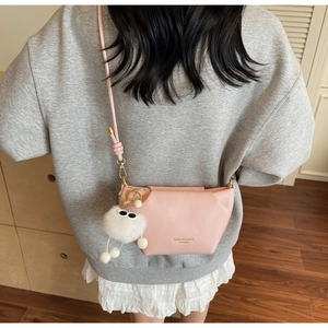 Sac bandoulière rose en cuir avec charm monstre en peluche porté en situation réelle