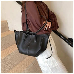 Close-up of black tote bag with white contrast stitching and grainy leather texture