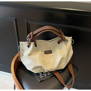 Dettaglio borsa tote in tela kaki con manici in pelle marrone su sedia nera minimalista
