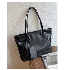 Macro detail of black oil wax leather tote bag with embossed logo and matte texture
