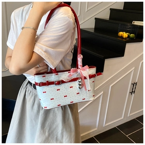 Dettaglio della borsa bianca stile balletcore con stampe a fiocco rosso e ciondolo a cuore