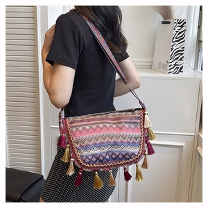 Detail shot of bohemian woven crossbody bag with colorful fringe and patterned strap