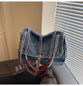 Détail du cabas en denim avec anses bordeaux, boucle métallique et coutures contrastées