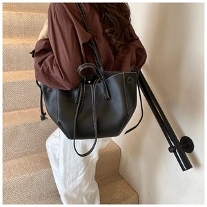 Detail of black litchi leather tote bag with white contrast stitching and side drawstrings