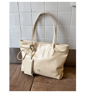 Detail of beige leather tote bag with PAN TOR logo and small hanging coin purse