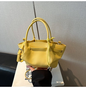 Detailed macro shot of yellow pebbled leather handbag with silver hardware accents