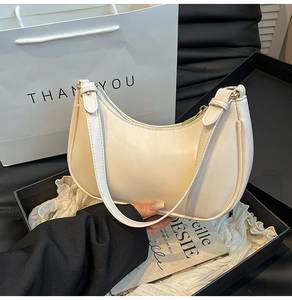 Detailed view of a cream half-moon hobo bag with zipper closure and matching strap