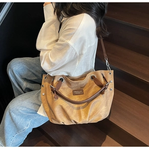 Dettaglio della borsa tote vintage marrone caramello con pieghe e occhielli in metallo argento