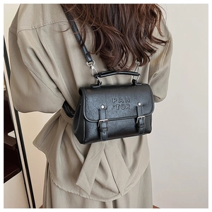 Detail view of black vintage leather backpack with embossed letters and metal buckles
