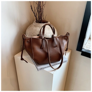 Detail of dark brown lychee leather tote bag featuring side drawstring and shoulder strap
