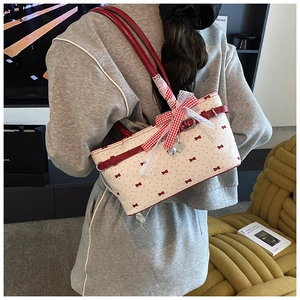 Foto lifestyle della borsa a spalla crema con fiocchi rossi e grande fiocco di pizzo