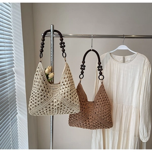 Detail of hand-crocheted hollow pattern and brown wooden bead handle on woven tote bag