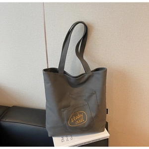 Close-up of canvas tote bag featuring double front pockets and yellow script embroidery