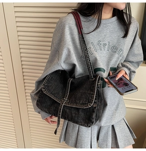 Détail du sac bandoulière rétro en denim noir délavé avec une sangle réglable assortie