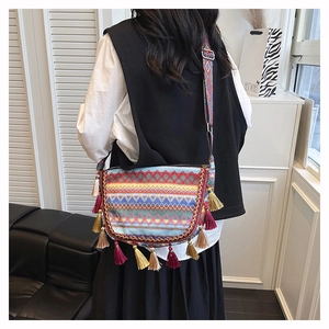 Detail of colorful woven ethnic crossbody bag with long fringes and patterned wide strap