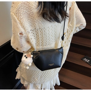 Détail du sac bandoulière noir en croissant avec texte doré et breloque mouton blanc