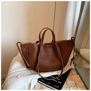 Detail of dark brown lychee leather tote with contrast stitching and dual handles