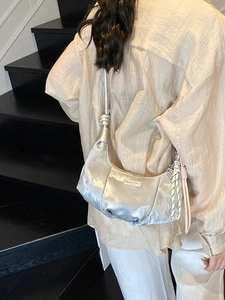 Silver metallic dumpling hobo bag with knotted strap and colorful braided pendants