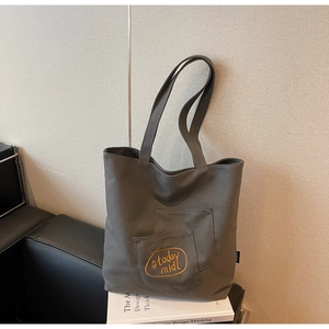Detail of grey canvas tote bag featuring yellow #today midi embroidery on the front pocket