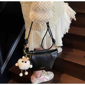 Détail du sac dumpling en cuir noir avec charm de monstre en peluche et logo doré