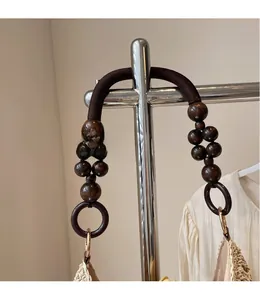 Close-up of woven straw tote bag with brown braided handles and decorative wooden beads