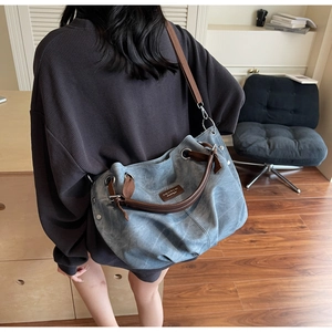 Detail showing the brown leather handle and vintage logo on a large blue tote bag