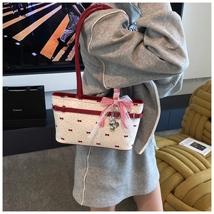 Dettaglio di una borsa a tracolla chic con fiocchi rossi e ciondolo a forma di cuore