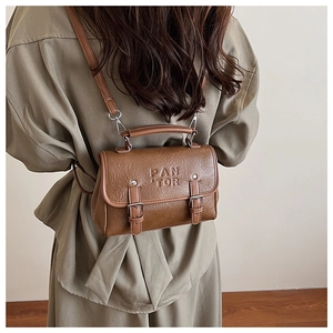 Rückansicht eines Models mit der braunen Retro-Quadrat-Tasche mit geprägtem Markenlogo