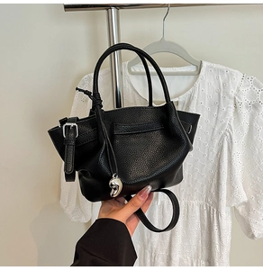 Detail of black pebbled leather bucket bag with silver charm and adjustable strap