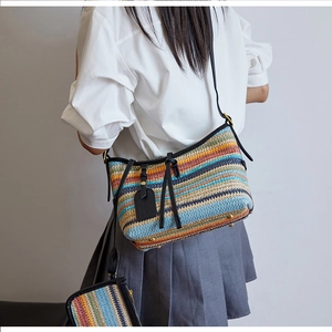 Detailed shot of striped straw woven crossbody bag and matching mini pouch on model