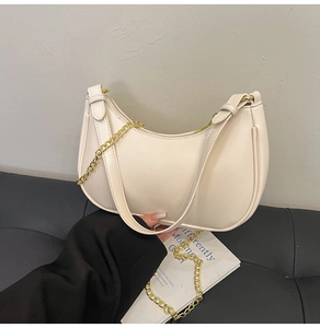 Detailed close-up of cream crescent underarm bag with gold chain and leather strap