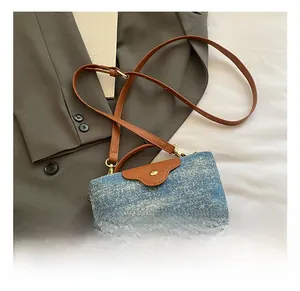 Detail showing the denim fabric contrast and brown leather flap with gold buckle